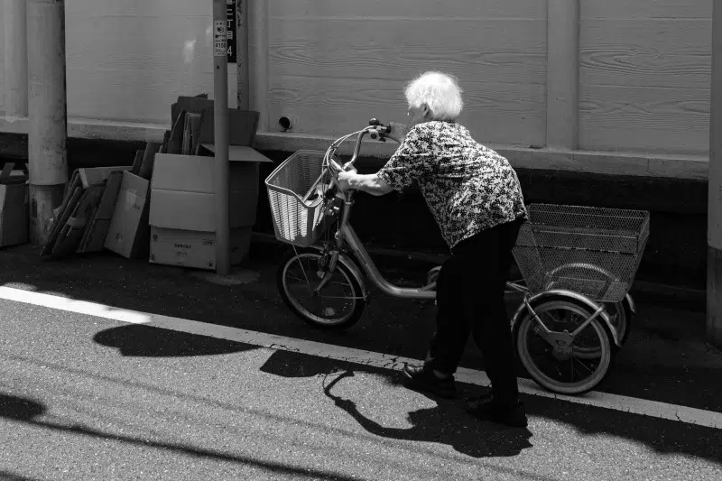 Black and white photo of grandma next to a bike in Japan